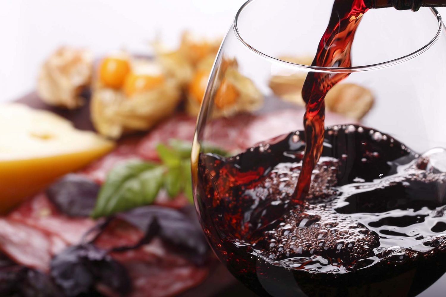 Pouring wine into glass and food background